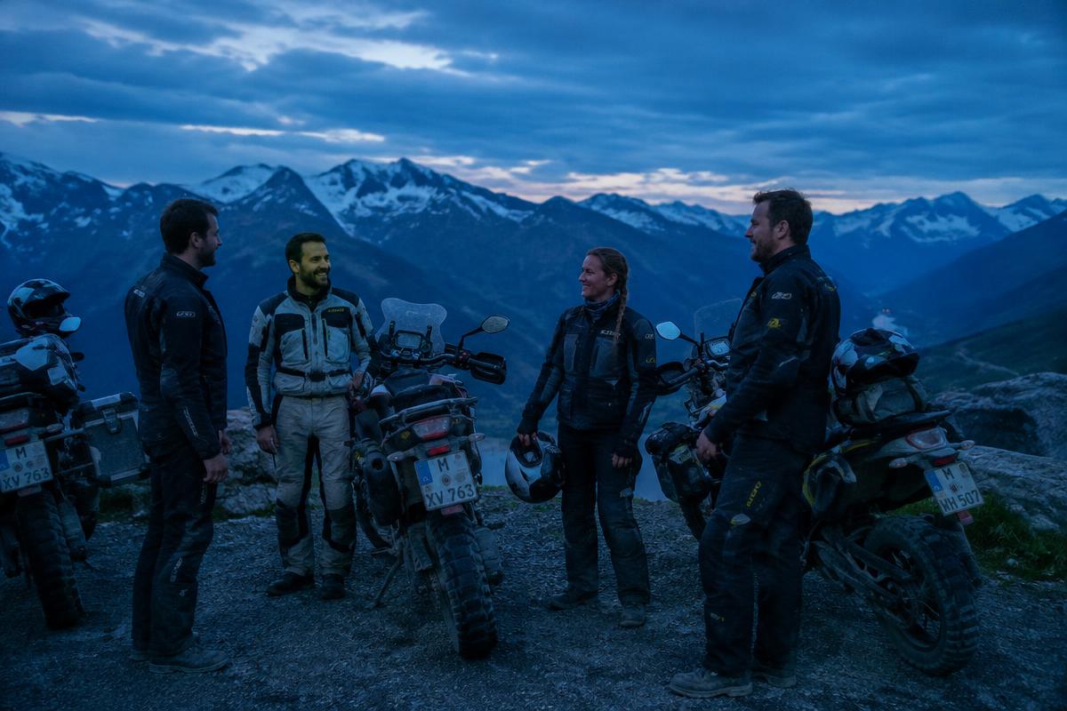 Riders gathered at a mountain pass at dusk